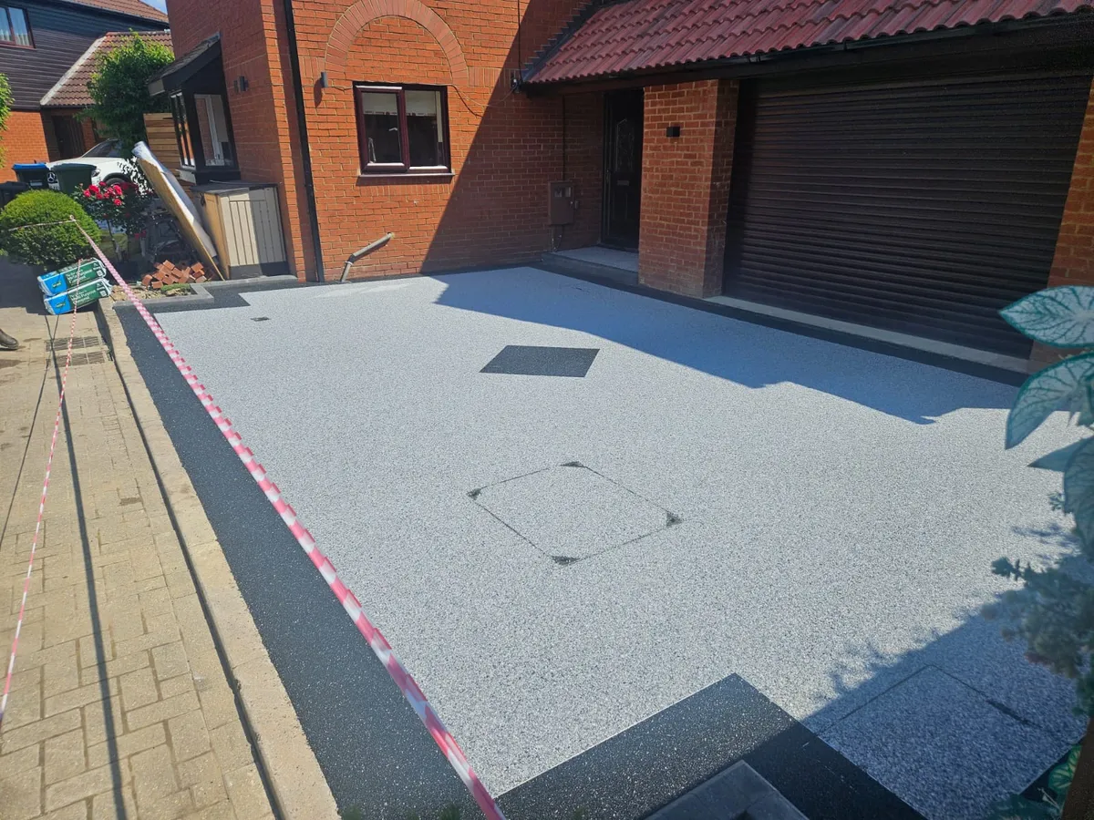 Silver grey resin driveway beside a garage